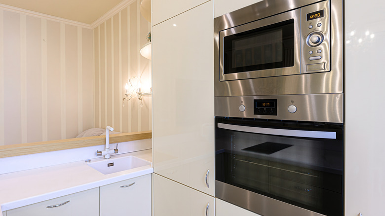 A clean and shiny stainless steel wall oven in a white kitchen.