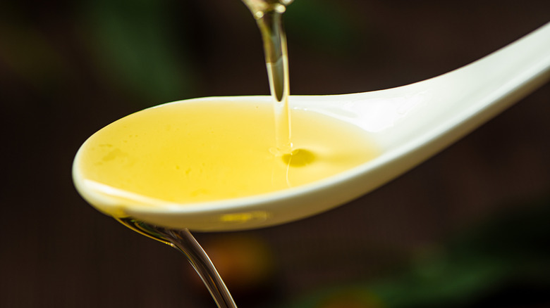 Close-up of olive oil pouring into spoon