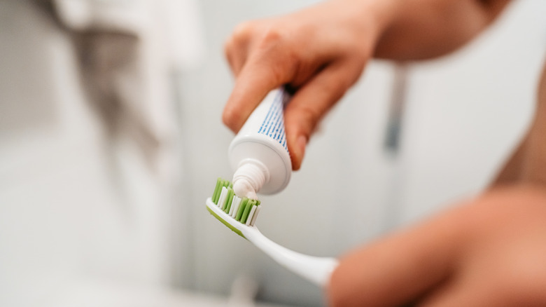 Close-up of person putting toothpaste on toothbrush