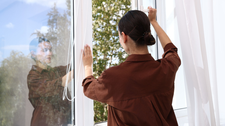 Woman opening window in her home