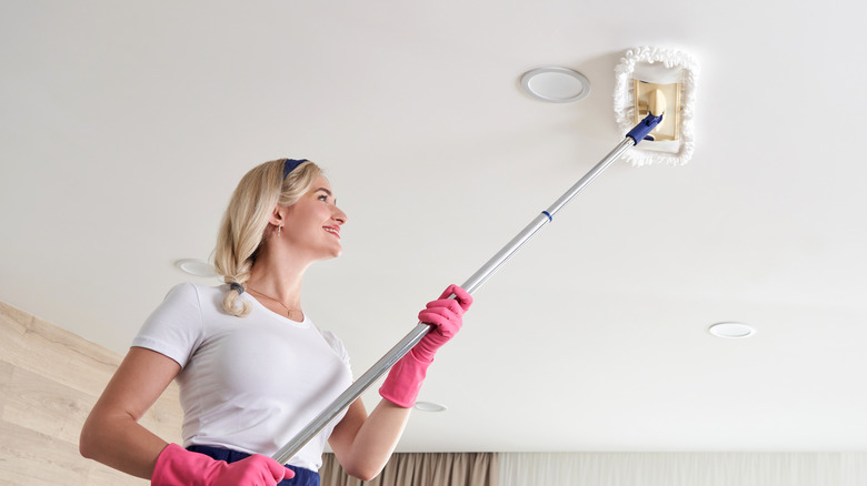 smiling woman mopping greasy kitchen ceiling