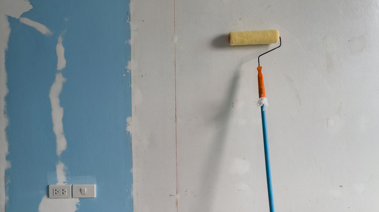 A clean paint roller sitting propped up against a wall