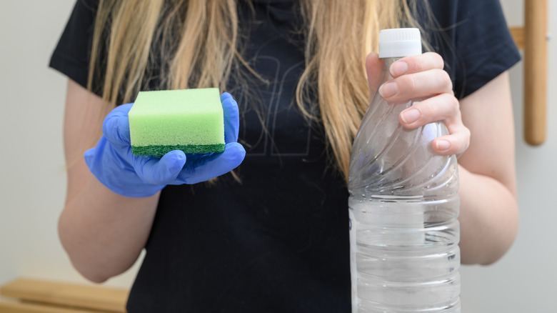 Cleaning supplies including a spray bottle, vinegar bottle, and rubber gloves