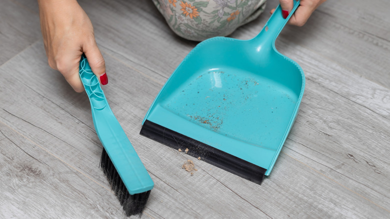 A person sweeping up debris on laminate floors
