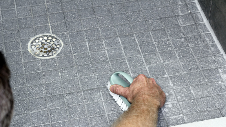 Person scrubbing shower tile grout