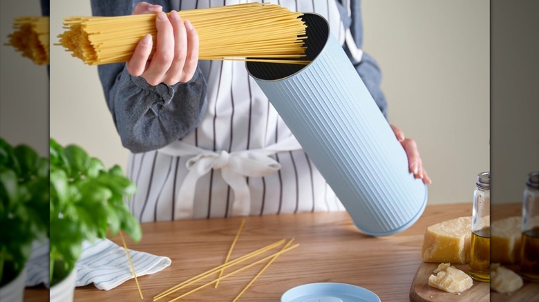Person putting pasta into BETTHAJ Tin with lid for spaghetti
