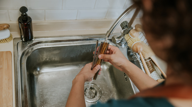 Woman rinsing straws in sink