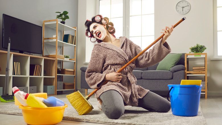 Woman playing air guitar on broom