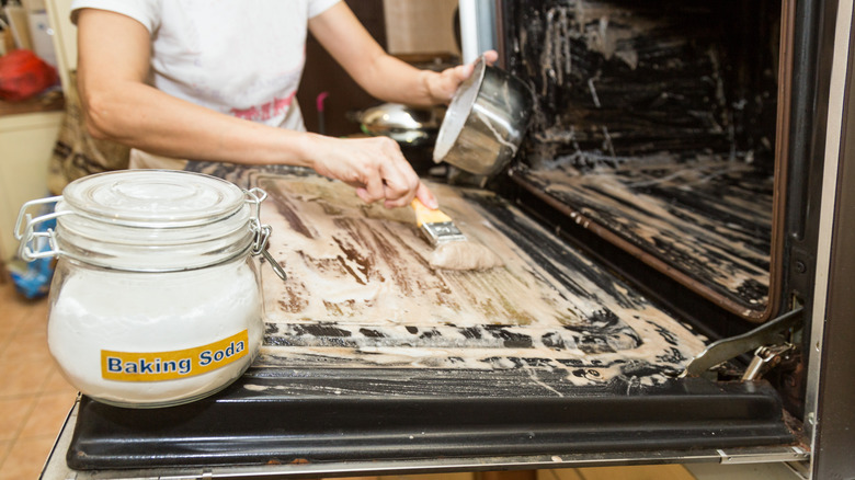 person cleaning oven with baking soda
