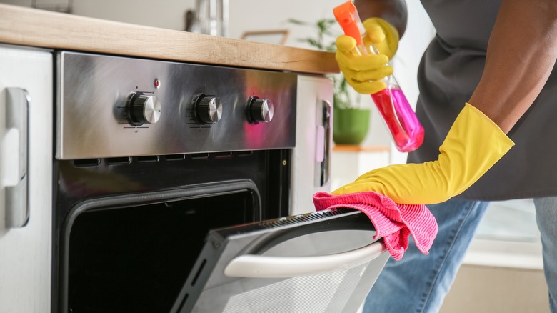 person spraying cleaner inside oven