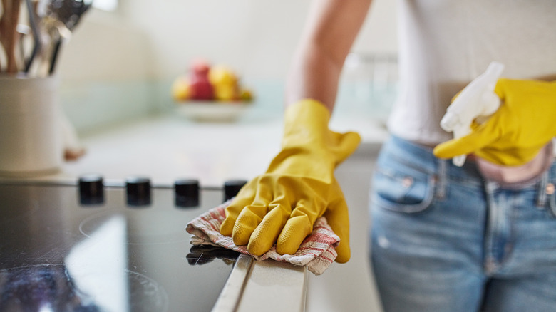 Woman in gloves cleaning kitchen