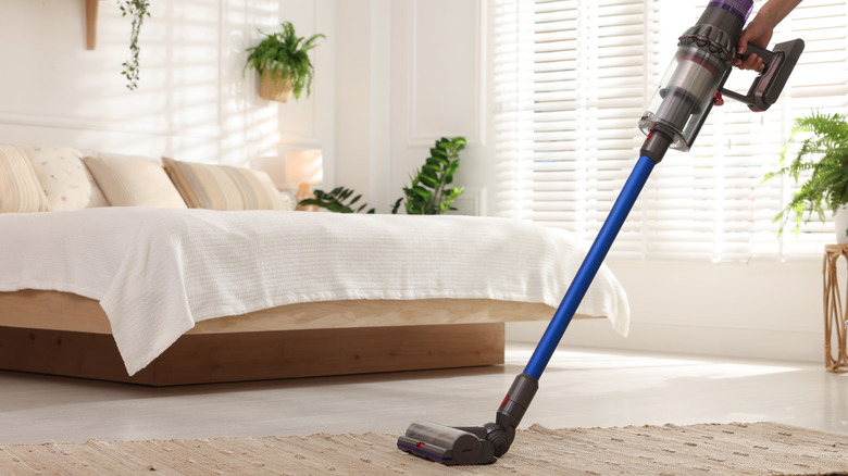 person vacuuming bedroom rug