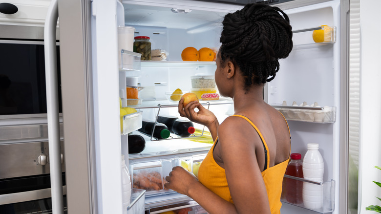 woman pulling food from fridge