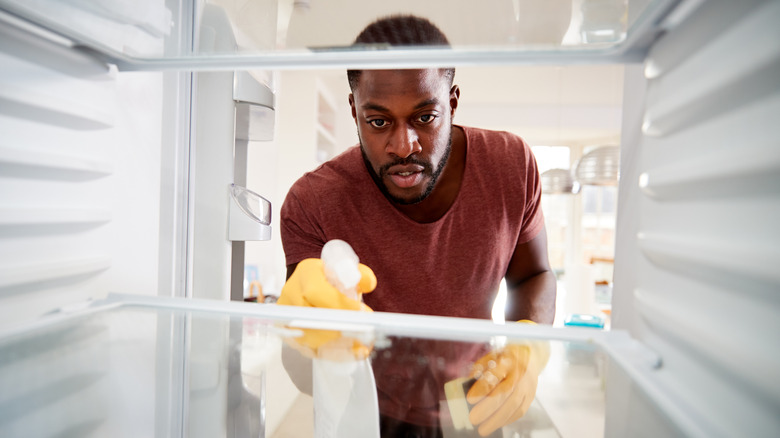 Young man cleaning fridge