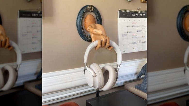 Wood artist's modeling hand mounted on the wall and used as a headphone holder