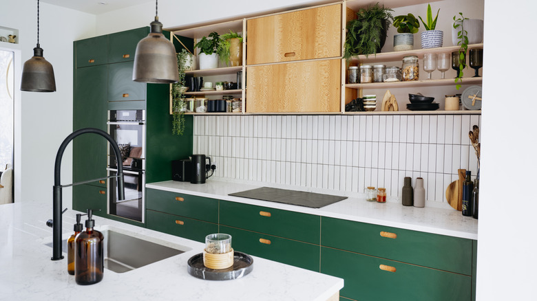 Kitchen with pendant lights, green colored cabinets, and tile backsplash