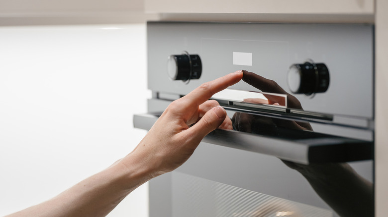 Woman pressing button on touchscreen display at modern electric oven