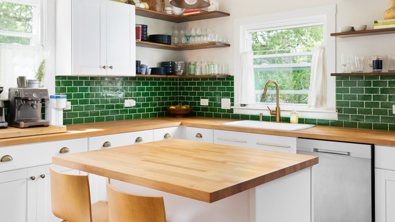 Contemporary kitchen with green subway tile backsplash and butcher block island.