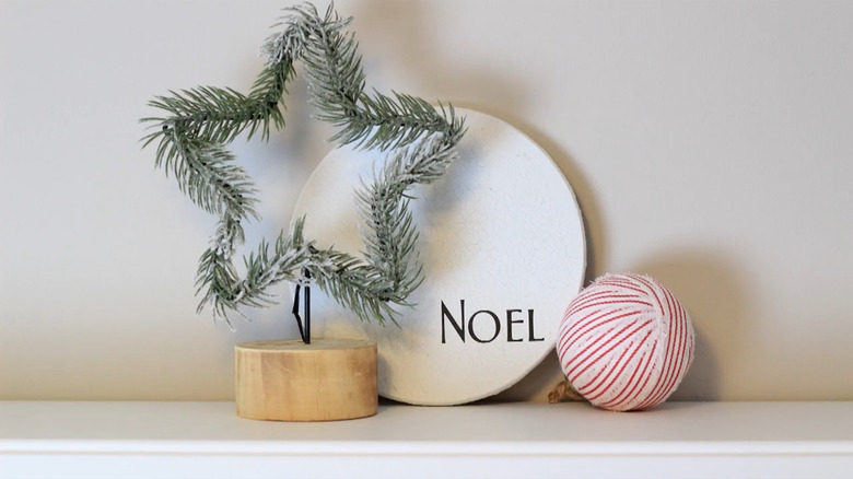 IKEA trivet painted white with the word "Noel" on it sitting behind a star decoration