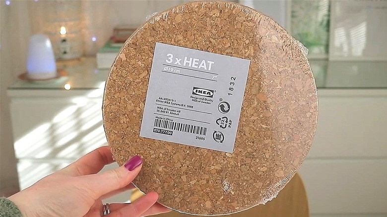 Person holding package of Ikea HEAT round cork trivets