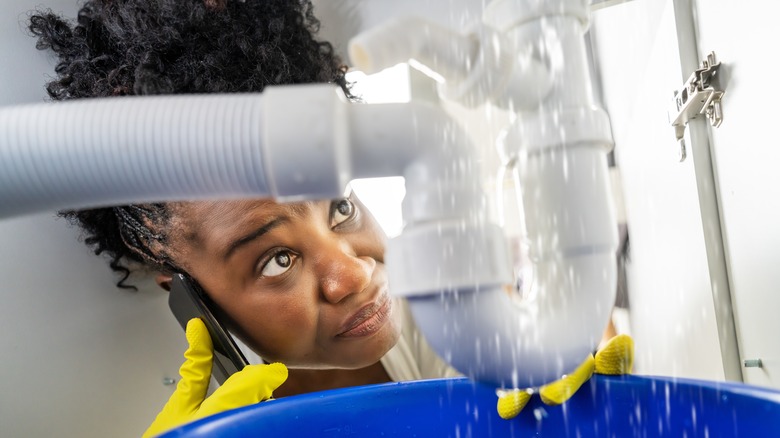 Woman looking at leaky pipe