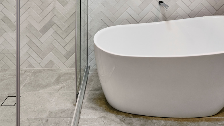 Close-up of wall, shower, and tub with light gray herringbone tile