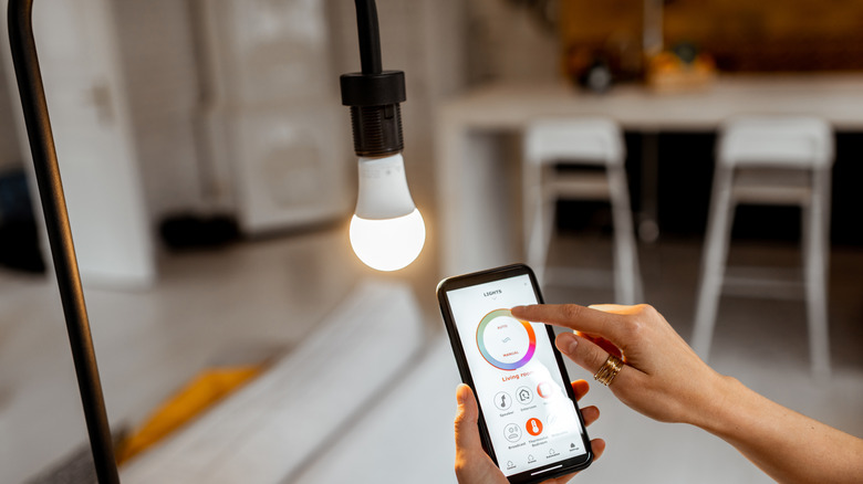 A person adjusting a smart lightbulb with a phone app