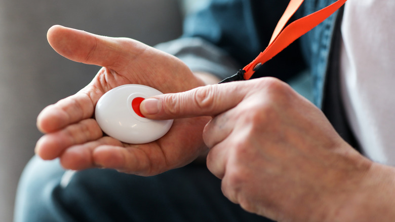 A person's hands pushing a handheld emergency button