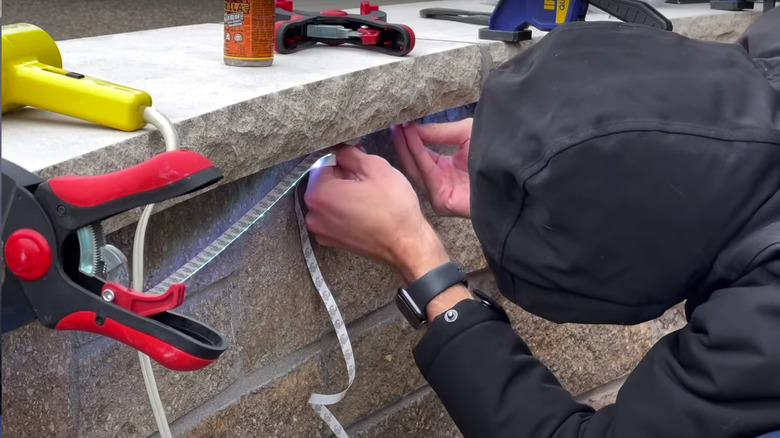 man installing strip lighting wall