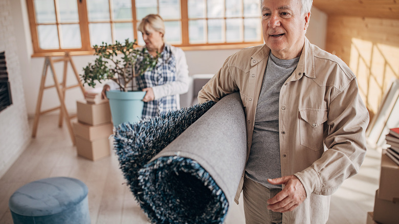 man with rolled carpet tucked in arm