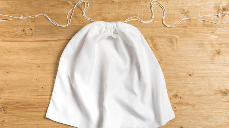 A white dust bag sitting empty on a wooden floor.