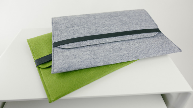 Two felt laptop sleeves sitting on a side table.