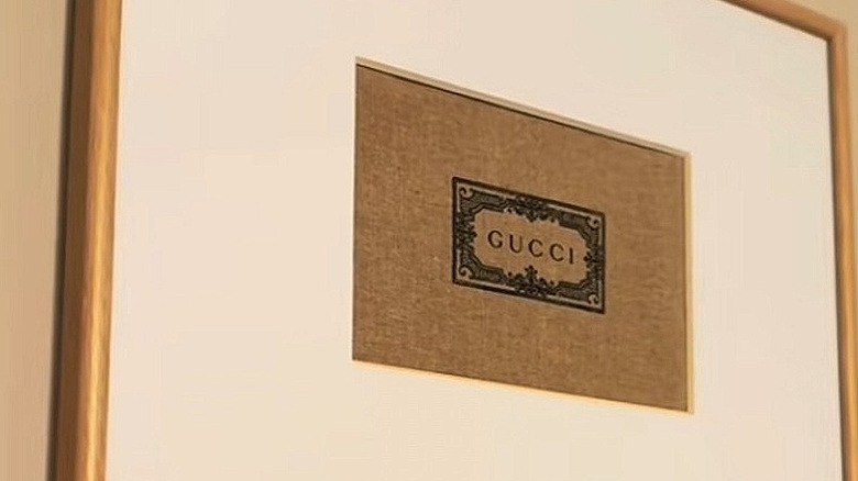 A Gucci dust bag framed on the wall.