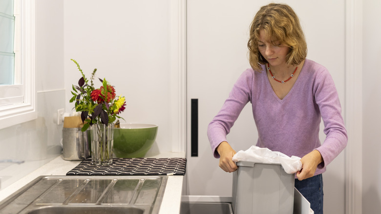 Woman putting in trash bag