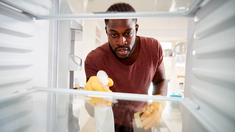 Man cleaning refrigerator interior