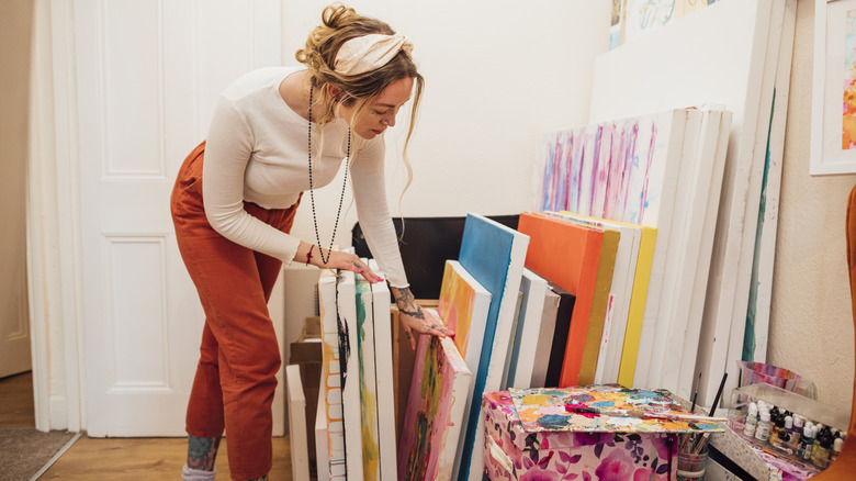 A woman browses through a bunch of artwork canvases
