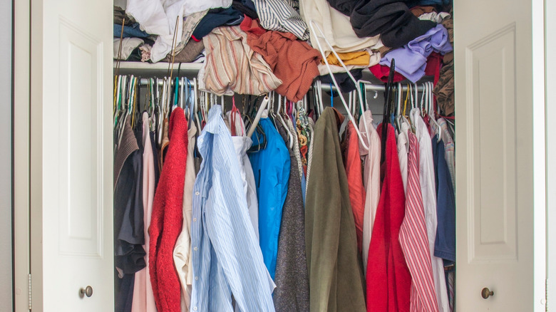 Clothes are piled up in a messy closet