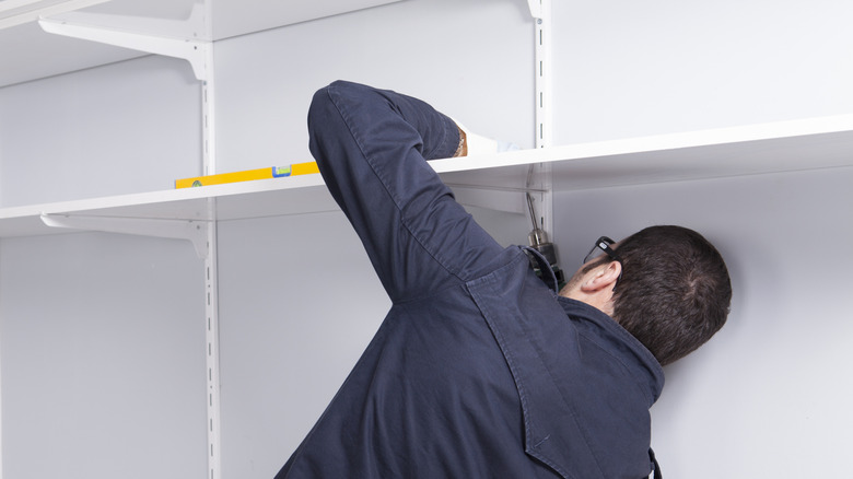 A man fitting closet shelves