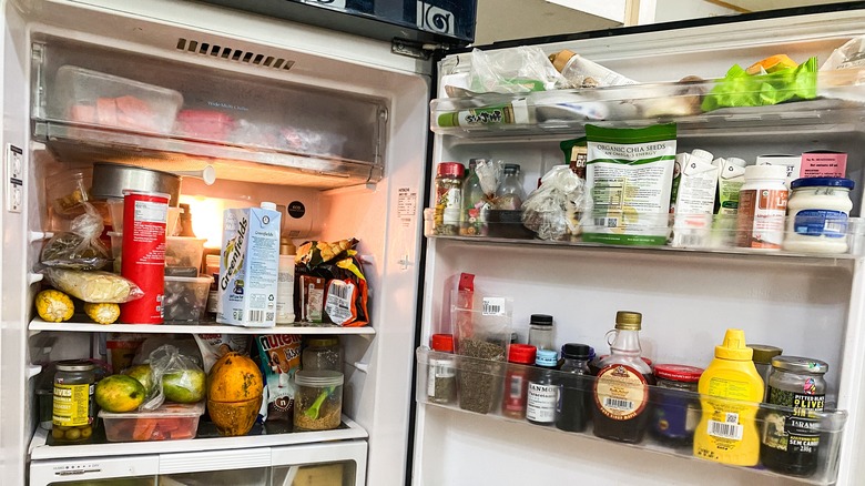 Cluttered, messy fridge with the door open