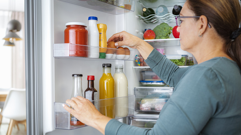 Woman placing eggs inside neatly organized fridge door