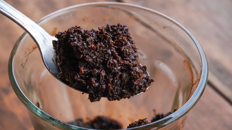 Spoonful of used coffee grounds lifted from glass cup