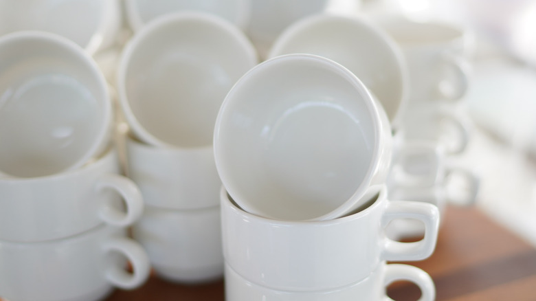 Stacks of white mugs sitting on a wood surface