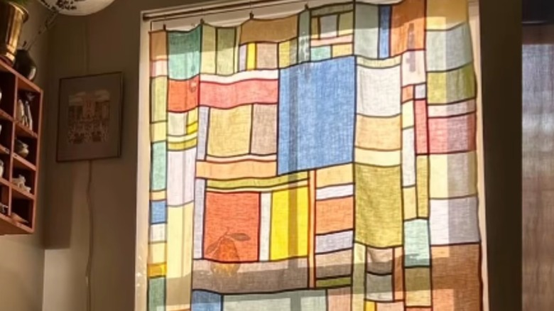 A patchwork curtain in a window resembles stained glass.