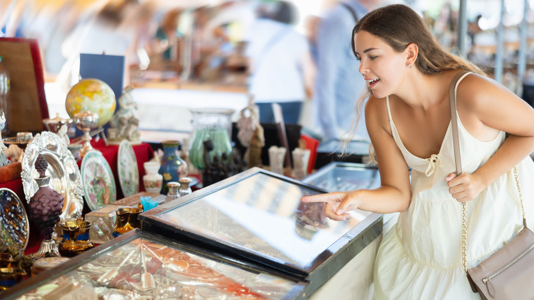 A person shopping for antique silver cutlery at a flea market