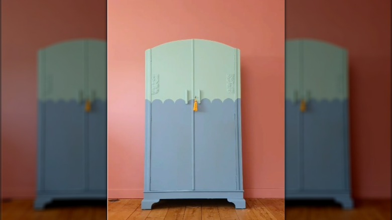 A free-standing closet paintined in blue and green color-blocking with a scalloped dividing line.