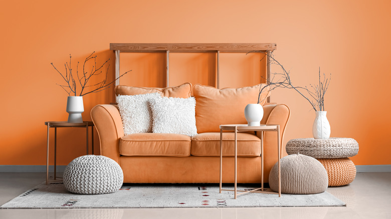 Modern living room interior with orange sofa and wall