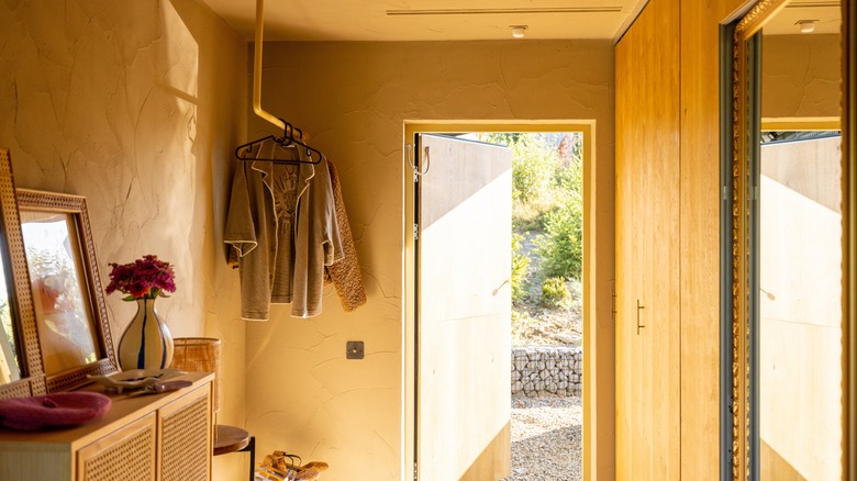An open door lets light into a cozy color drenched entryway