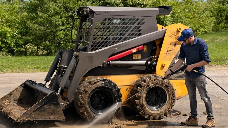 Man power-washing construction equipment