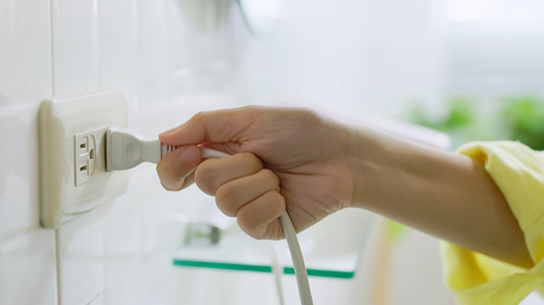 Hand on cord plugged into wall