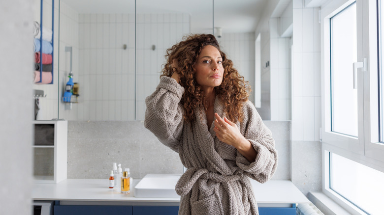 Woman in robe standing in bright, white bathroom